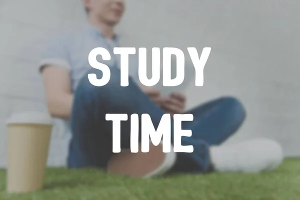 Tiro cortado de jovem sentado na grama e usando tablet, inscrição tempo de estudo — Fotografia de Stock