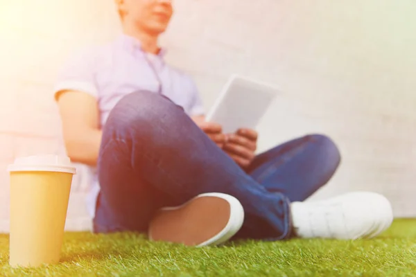 Обрізаний знімок молодого чоловіка, що сидить на траві і використовує планшет — стокове фото