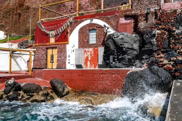 Spruzzata d'acqua dal mare Egeo vicino all'edificio rosso sull'isola greca — Foto stock