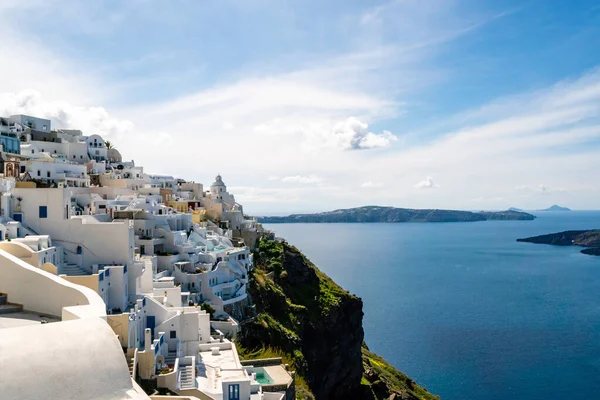 Sunshine on white houses near tranquil aegean sea against sky with clouds in Santorini — Stock Photo