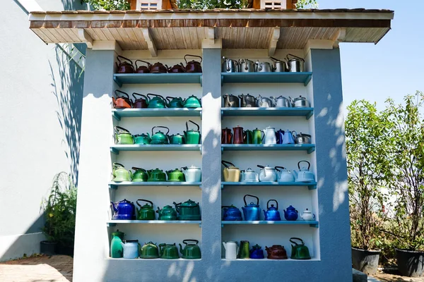 Sunlight on retro and colorful teapots on shelves near plants — Stock Photo