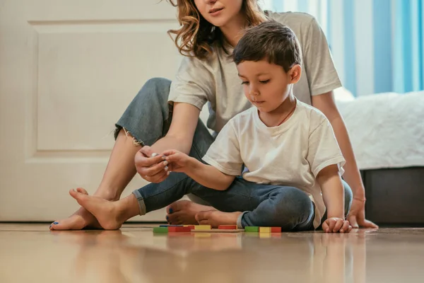 Madre giocare con bambino figlio mentre seduto vicino giocattoli sul pavimento — Foto stock