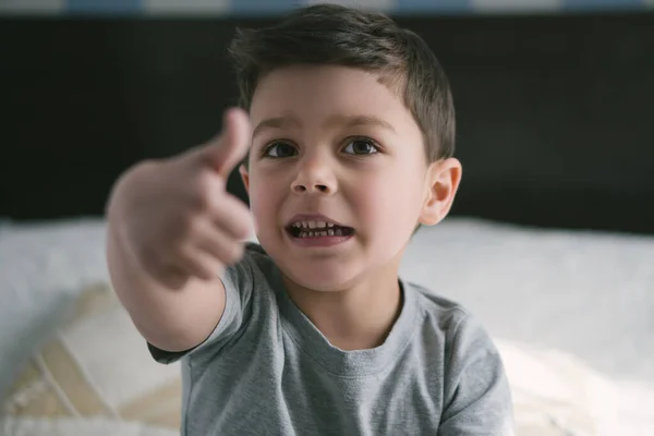 Messa a fuoco selettiva di carino bambino ragazzo che punta con il dito e guardando la fotocamera a casa — Foto stock