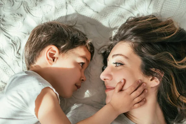 Vista dall'alto di carino bambino ragazzo toccare il viso della madre attraente — Foto stock