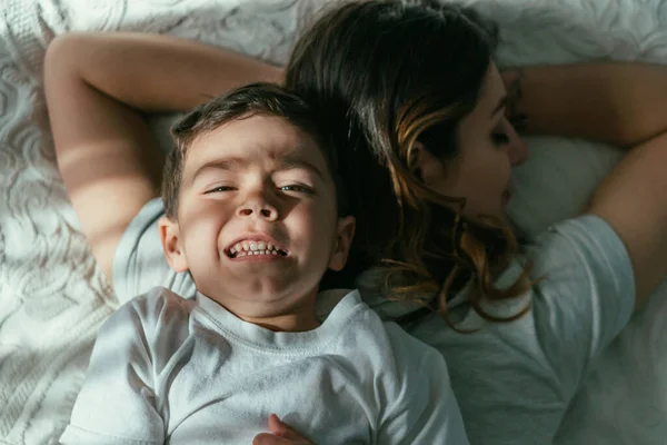 Top view of toddler boy lying on back of mother in bedroom — Stock Photo