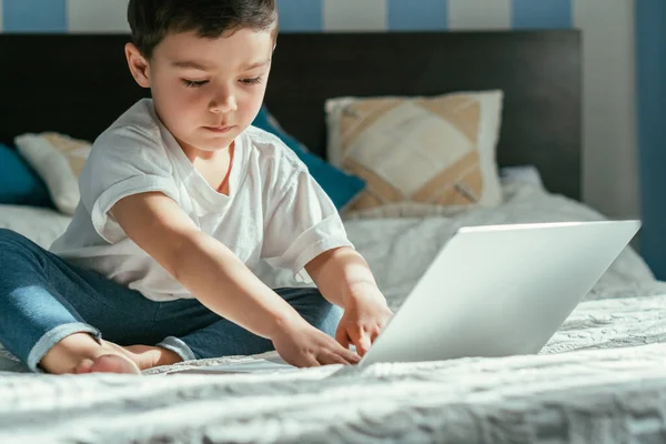 Вибірковий фокус милий хлопчик-малюк використовує ноутбук у спальні — стокове фото