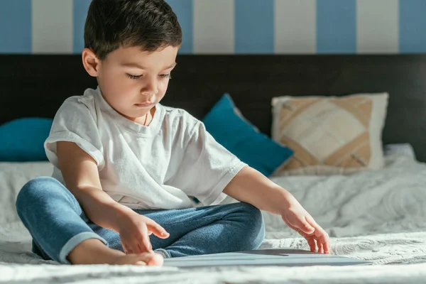 Selektiver Fokus des niedlichen Kleinkindes, das Laptop im Schlafzimmer berührt — Stockfoto