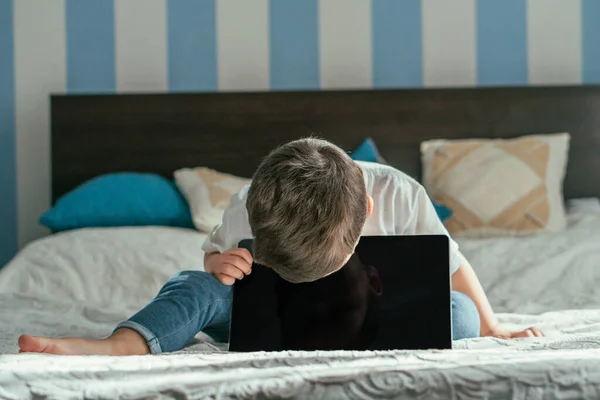 Selective focus of toddler boy touching laptop with blank screen in bedroom — Stock Photo