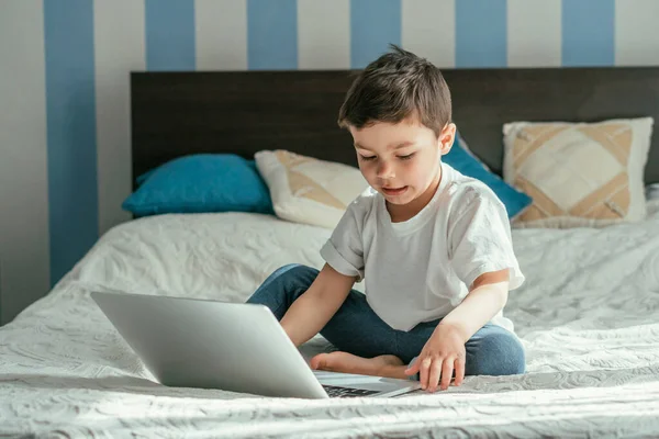 Enfoque selectivo de niño adorable usando el ordenador portátil en el dormitorio - foto de stock