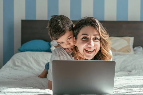 Cute toddler boy near cheerful freelancer mother at home — Stock Photo