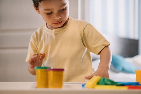 Selektiver Fokus des entzückenden Kindes, das mit buntem Knetmasse spielt — Stockfoto