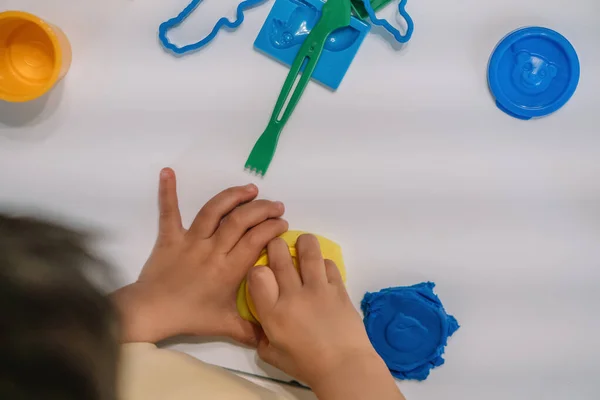 Vue de dessus des figures de plasticine de garçon sculptant près du bâton et des moules sur la table — Photo de stock