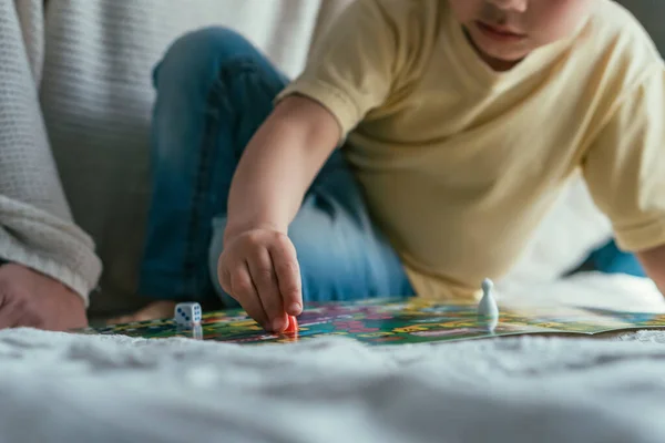 Vue recadrée du petit garçon jouant au jeu de société sur le lit, mise au point sélective — Photo de stock