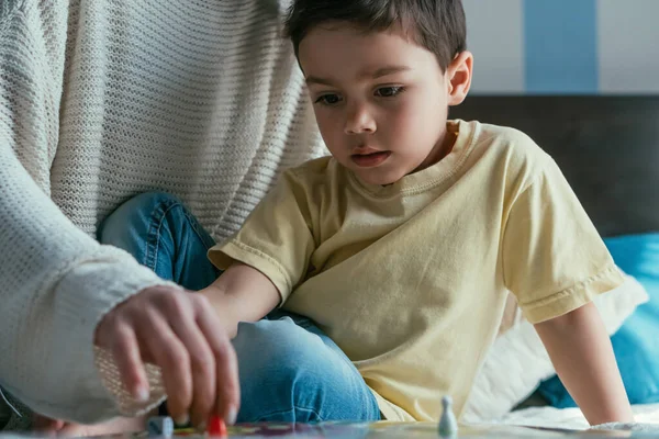 Visão cortada de mulher jogando jogo de tabuleiro junto com filho adorável na cama — Stock Photo