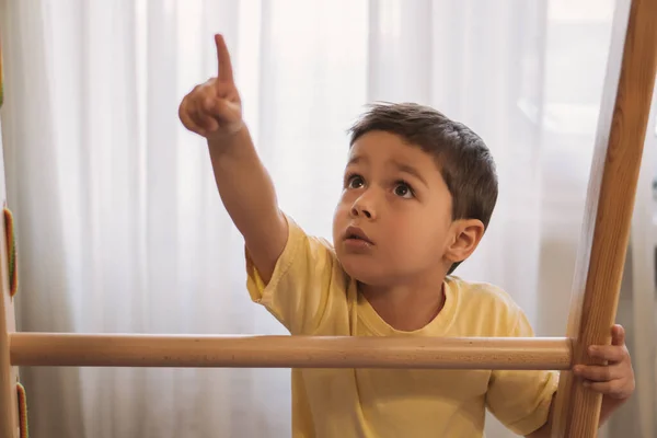 Lindo chico apuntando con el dedo mientras se toca escalera de casa gimnasio - foto de stock