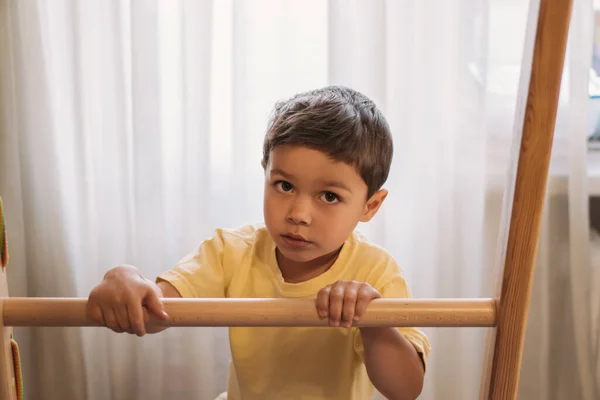 Adorable niño mirando a la cámara mientras se toca escalera de casa gimnasio — Stock Photo