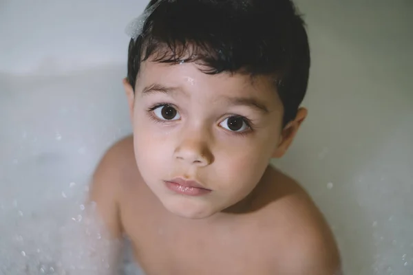 Overhead view of adorable boy looking at camera while taking bath — Stock Photo