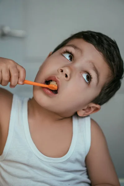 Carino bambino guardando verso l'alto mentre lavarsi i denti in bagno — Foto stock