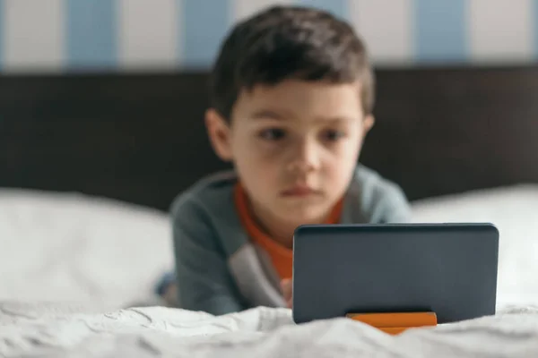Selektiver Fokus des niedlichen, aufmerksamen Jungen, der im Schlafzimmer auf das Smartphone schaut — Stockfoto