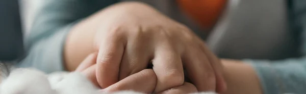 Teilansicht des Kindes, das mit geballten Händen auf dem Bett liegt, panoramische Ernte — Stockfoto