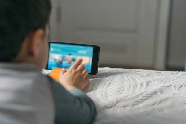 Selektiver Fokus des Jungen, der den Bildschirm des Smartphones berührt, während er Online-Unterricht schaut — Stockfoto