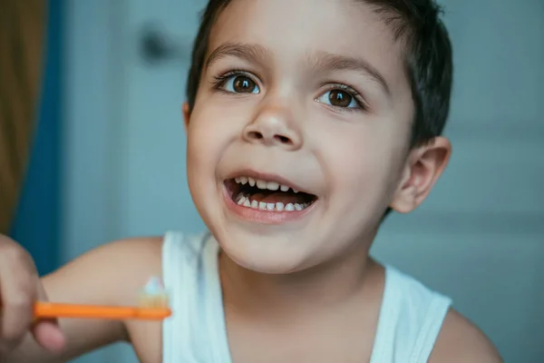 Foco seletivo de menino alegre segurando escova de dentes com pasta de dentes — Fotografia de Stock