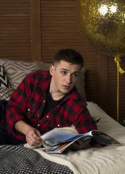 Ein junger Mann im Hipster-Hemd liegt auf einem Bett — Stockfoto