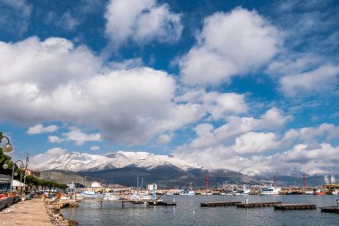 Gaeta 'nın deniz manzarası, bulutlu gökyüzü ve arka planda karlı dağlar..