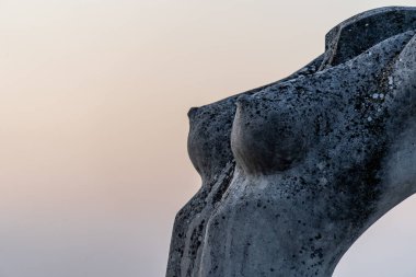 Atri, Teramo, İtalya, Ağustos 2019: Eski Atri kasabasında kadın göğüs heykelinin yakın çekimi, arka planda kızıl gün batımı gökyüzü.