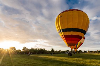 Paestum, İtalya, Eylül 2019: Günbatımında yeşil bir alanda renkli sıcak hava balonu
