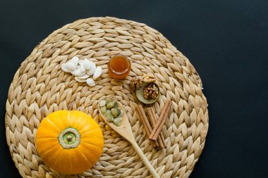 Küçük kabak tohumu, tahta kaşık, soyulmuş tohumu ile bal, ceviz ve tarçın peçeteye daire mat/su sümbül siyah bir zemin üzerine yapılmış küçük cam olabilir