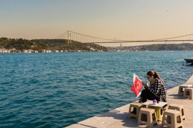 Kimliği belirsiz bir kadın boğaz manzarasında Türk bayrağı arka üzerinde tutar. Istanbul,Turkey.15 Nisan, 2017