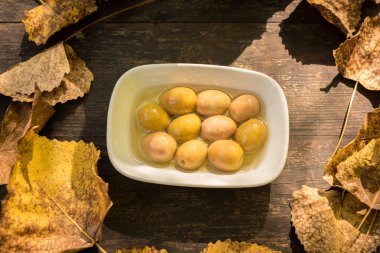 Arka plan doku eski ahşap masa ve üstten görünüm içinde sarı sonbahar yaprakları büyük yeşil zeytin ile bir daire şeklinde katlanmış. Kopya alanı düzenlemek için