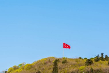 Istanbul, Türkiye'de rüzgar bir tepe üzerinde mavi bir gökyüzü ile Türk bayrakları sallayarak görünümü.