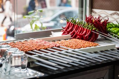 Birkaç Adana kebap şişleri pişmiş ve hizmet için bekleyen kaplı. Ham Türk geleneksel Sish kebab, et, karaciğer, sığır eti, et bir restoranda aşçı için hazır. Arka plan üzerinde ızgara için bile delip yeşil ve kırmızı biber.