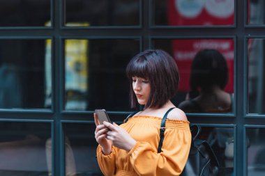 Güzel kız ayakta dururken akıllı telefon kullanır ya da mesaj atar