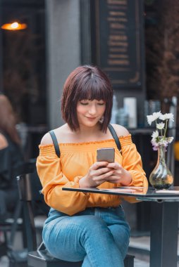 Güzel kız bir kafede akıllı telefon kullanıyor.