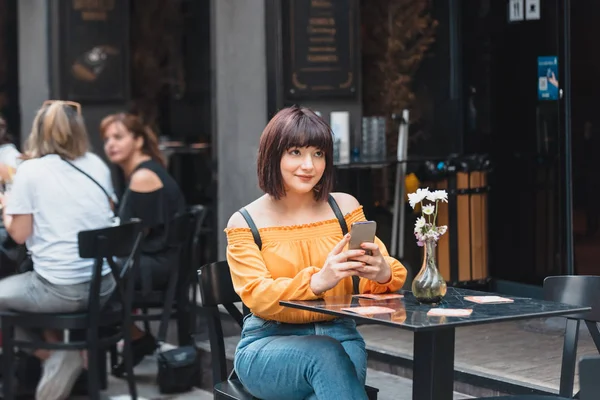 Красивая девушка пользуется смартфоном в кафе — стоковое фото