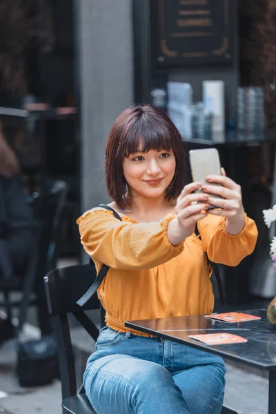 Красивая девушка делает селфи с мобильного телефона в кафе — стоковое фото