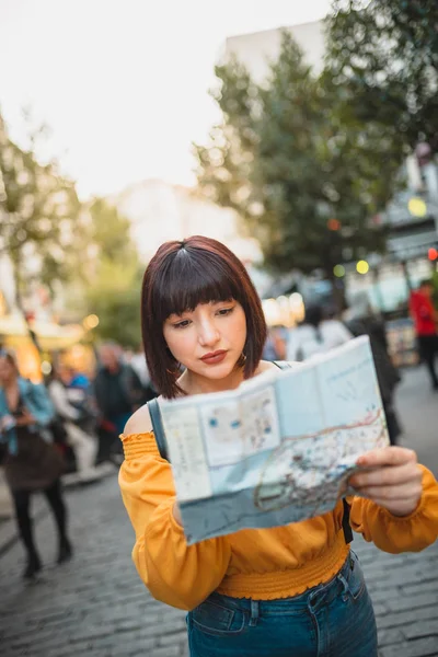 Симпатичная девушка прокладывает улицы города с картой — стоковое фото