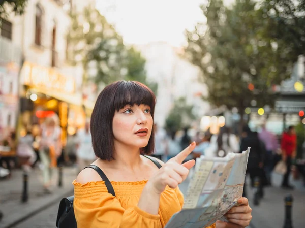 Симпатичная девушка прокладывает улицы города с картой — стоковое фото