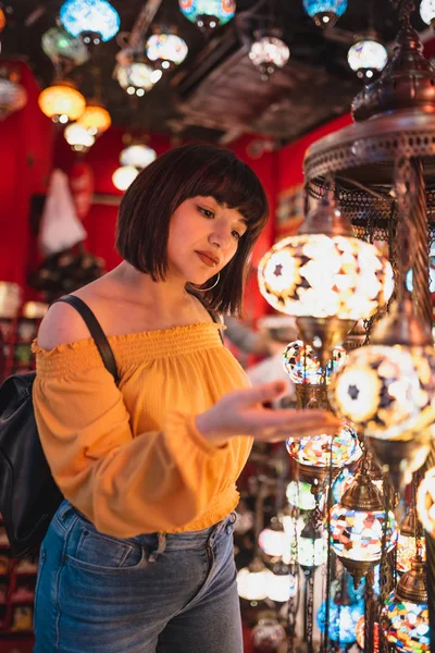 Симпатичная девушка выглядит традиционные лампы в магазине — стоковое фото