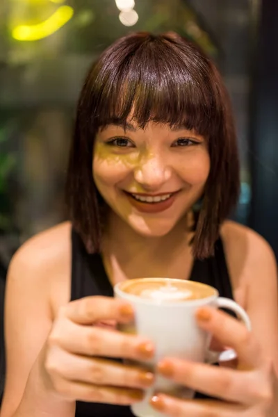 Красивая молодая девушка пьет кофе в кафе — стоковое фото
