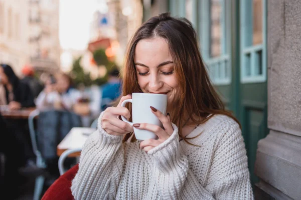 Красивая молодая девушка в кафе на открытом воздухе пьет кофе — стоковое фото
