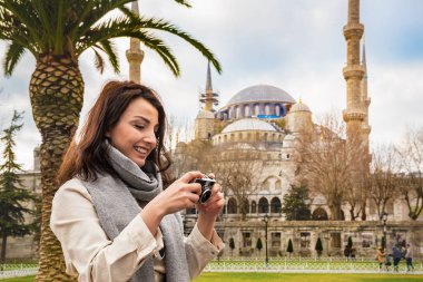 İstanbul, Türkiye 'de turistler ve turistler için popüler bir yer olan Sultanahmet Camii veya Mavi Cami manzaralı güzel bir kadın turist fotoğrafı çekti