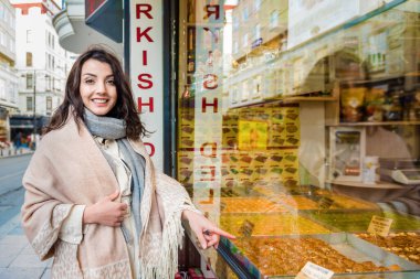 Güzel gezgin kadın geleneksel Türk tatlısına bakıyor. Baklava İstanbul, Türkiye 'de bir mağaza sattı. Gezgin kadın yaşam tarzı kavramı..