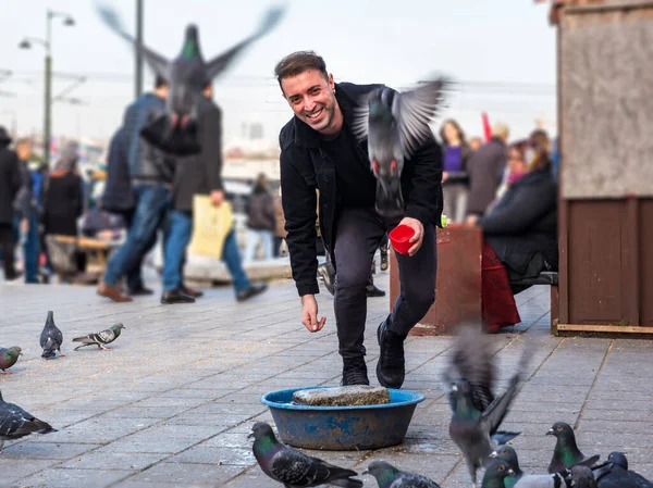 Bulanık görüntü: Moda kıyafetleri içindeki yakışıklı adam Eminonu, İstanbul ve Türkiye 'deki yeni cami meydanında güvercinleri besliyor