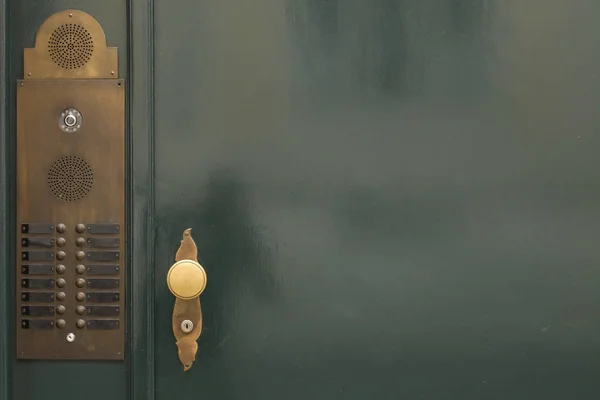 Green door with golden knob and bells