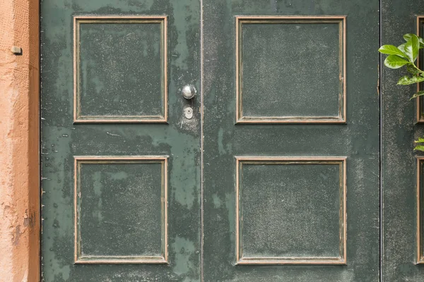 Porta de madeira pintada verde com padrão quadrado laranja — Fotografia de Stock