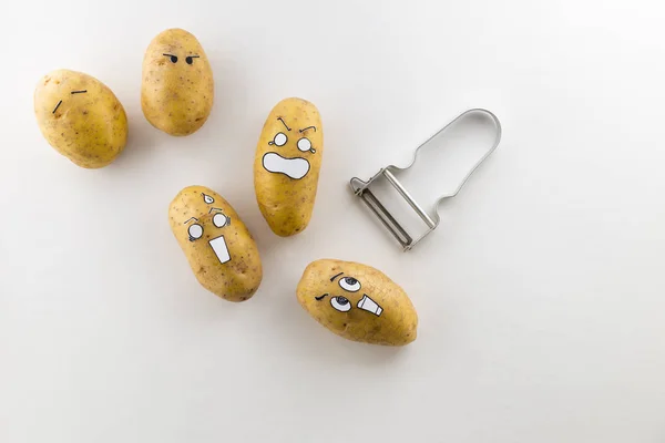 Przerażające oblicze ziemniaki i obieraczki na białym tle — Zdjęcie stockowe